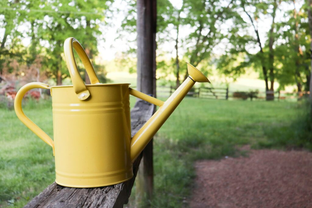 A yellow watering can resting on a timber post