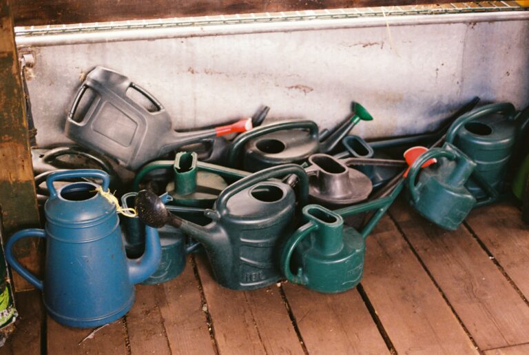 A heap of plastic watering cans on timber floorboards