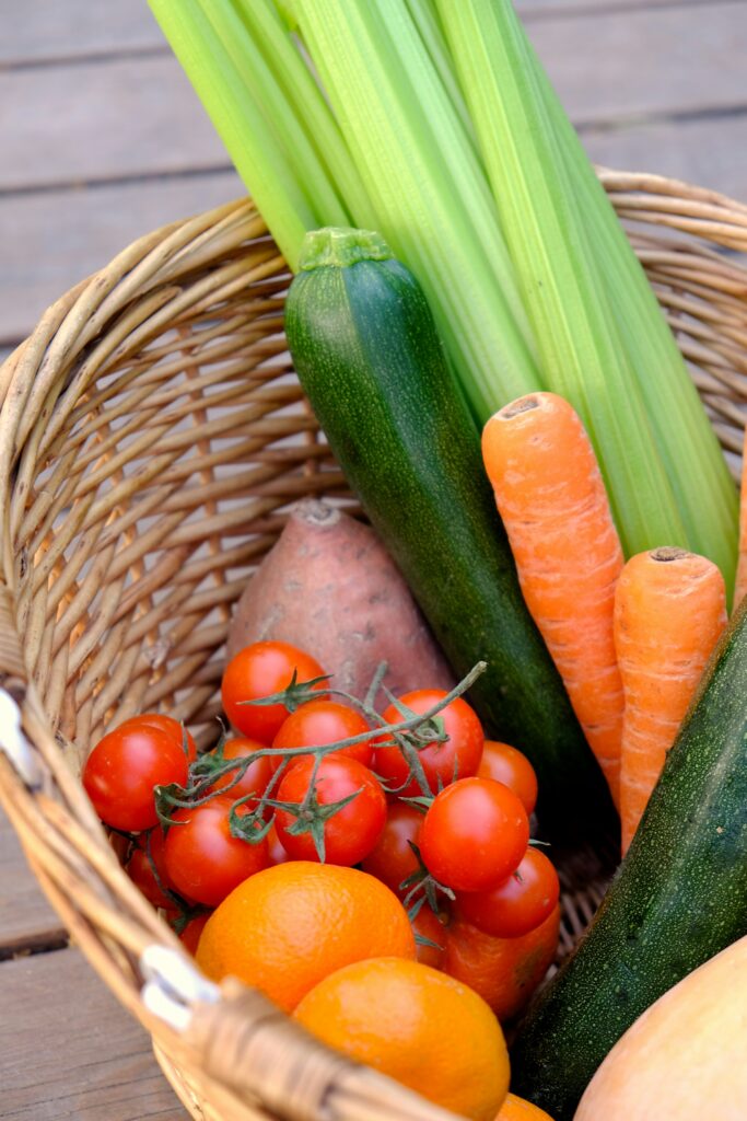 A woven basket of carrots, zucchini and cherry tomatoes