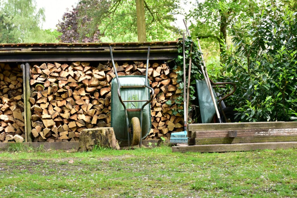 A green wheelbarrow leaning on a stack of firewood